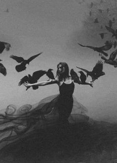 a black and white photo of a woman surrounded by birds in the air with her arms outstretched