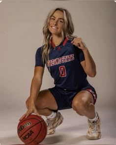 a female basketball player is posing for a photo with her foot on the basketball ball