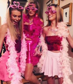 three women dressed in pink and white posing for the camera