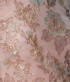 an embroidered fabric with gold and blue flowers on pink velvet, close - up view