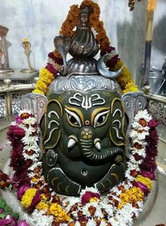 an elephant head statue is surrounded by flowers and garlands in a temple or shrine