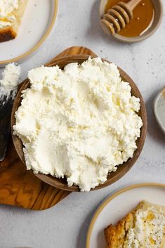 there is a bowl of cottage cheese on the table next to other plates and utensils