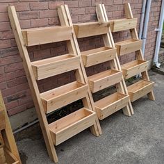 several wooden shelves lined up against a brick wall next to a planter and ladder