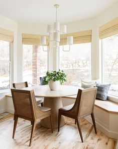 a dining room table surrounded by chairs and windows