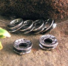 three metal rings sitting on top of a rock next to a green plant with leaves