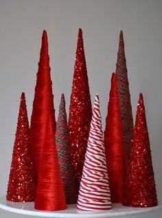 red and silver christmas trees are on a white shelf with glittery cones in the middle