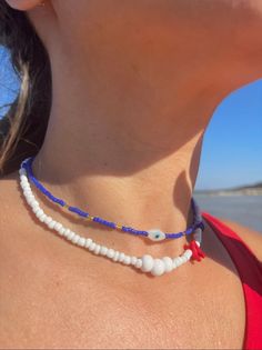 Tropical style white beaded choker with red shell accents and evil eye beads. The blue evil eye choker this necklace is paired with is called the 'Kara Choker'. Shark Teeth Crafts, Evil Eye Choker, Evil Eye Beads, Shark Tooth, Tropical Style, Eye Beads, Blue Evil Eye, Shark Teeth, Evil Eye Necklace