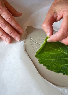 two hands are working on a piece of paper that has been carved into the shape of a heart