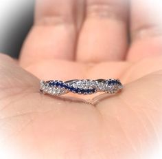 a woman's hand holding a diamond and blue sapphire wedding band in white gold