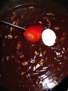 a chocolate dessert with strawberries and nuts on top is ready to be eaten by someone