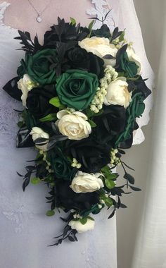 a bridal bouquet with white and green flowers on the bride's wedding dress