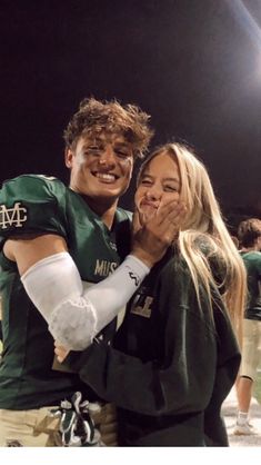 a man and woman hugging each other at a football game