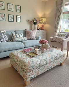 a living room filled with furniture and flowers on top of a coffee table in front of a window