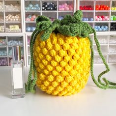 a crocheted bag sitting on top of a table next to a perfume bottle