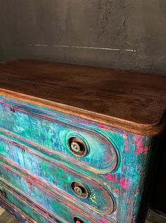 an old dresser painted in blue and green with rusted knobs on the drawers