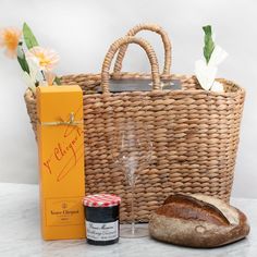 a basket with bread, wine glasses and an orange box next to it on a table