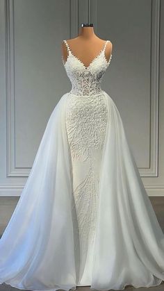 a white wedding dress on display in front of a wall with an open back and long train