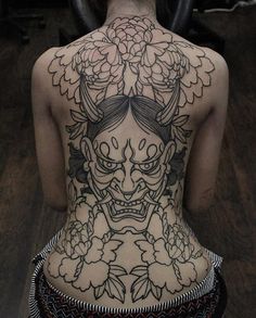 the back of a woman's body with tattoos and flowers on her head,