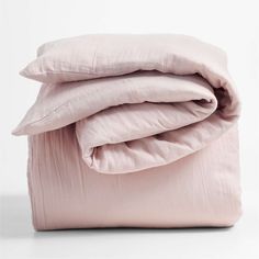 the pink sheets and pillows are folded up on top of each other in front of a white background