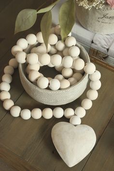 a white heart shaped object sitting on top of a wooden table next to a plant