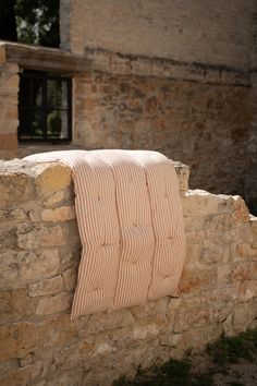 a towel hanging on the side of a stone wall next to a brick building with a window