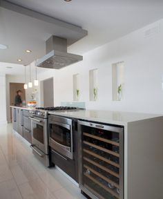 a modern kitchen with stainless steel appliances and marble counter tops, along with white tile flooring