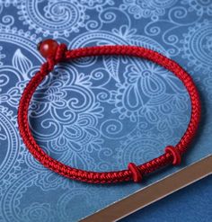 a red string bracelet with a wooden bead on top of a blue tablecloth