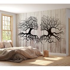 a bedroom scene with focus on the bed and tree wall decal in the background