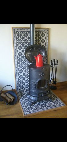 an old fashioned stove sitting on top of a wooden floor next to a tile wall