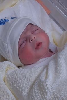 a baby is laying down in a crib wearing a white blanket and headgear