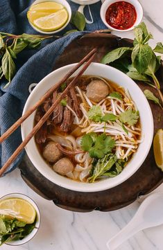 a white bowl filled with meat and vegetables next to chopsticks on top of a table