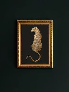 a gold framed art piece with a leopard on it's back legs and tail