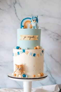 a three tiered cake decorated with cats and rainbows is on top of a table