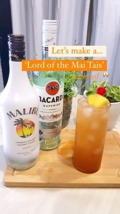 a wooden tray topped with a bottle of alcohol next to a bowl of fruit and a drink