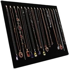 an assortment of necklaces are displayed on a black display board with white trimming