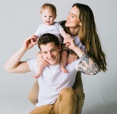 a woman holding a baby and smiling at the camera while sitting on her dad's lap