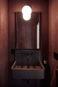 a bathroom sink under a round light in a room with purple walls and flooring