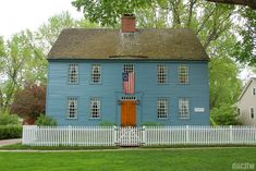 a blue house with an american flag on it's front door and white picket fence