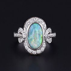 Opal and Diamond Ring: Experience the timeless beauty of this semi-black opal elegantly encased in 18k white gold and adorned with sparkling diamonds. The face of the 1990s ring measures 0.75 inches by 0.5 inches wide, and it is in great condition.  The ring is a size 6.5, but it can be resized free of charge. Your ring will arrive elegantly packaged, ready for gifting or as a special treat for yourself. Each piece is carefully wrapped to ensure a delightful unboxing experience. We also offer fr Formal Opal Ring With Polished Finish, Formal Multi-stone Opal Ring With Diamonds, Formal Multi-stone Diamond Opal Ring, Luxury Diamond Opal Ring For Formal Occasions, Luxury Opal Gemstone Ring For Formal Occasions, Luxury White Gold Opal Ring, Luxury White Gold Opal Ring For Formal Occasions, Exquisite Multi-stone Opal Ring For Formal Occasions, Classic Multi-stone Opal Ring For Formal Occasions