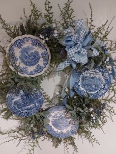 an arrangement of blue and white plates is arranged on the wall with greenery around it