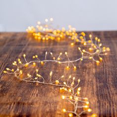 some small yellow flowers are on a wooden table with lights in the shape of branches