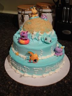 there is a blue cake decorated with animals and fish on the bottom tier, along with other decorations