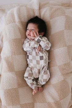 a baby laying on top of a bed covered in blankets