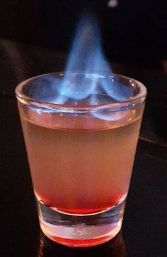 a close up of a glass with a liquid in it and a blue flame coming out of the top