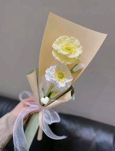 two yellow flowers are tied together on a black leather couch with a white ribbon around it