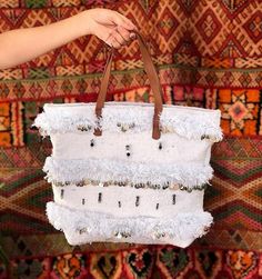 this handbag makes your style more unique and special because it's handmade 100% with much love... I made it with my mom by using  hand-woven tissue by the women of Artissma Foundation which means :"Art du Tissage Marocain".  PS: (Don't forget to check our story) https://www.etsy.com/your/shops/artissma/tools/listings So, this bag is made by white woolen threads with genuine brown leather, and decorated by different Berber design inspired by nature and Moroccan culture and Moroccan wedding blank Moroccan Inspiration, Moroccan Wedding Blanket, Bohemian Bag, Moroccan Culture, Moroccan Wedding, Wedding Blankets, Bohemian Bags, White Handbag, How To Make Handbags