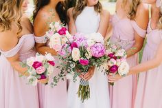 a group of women standing next to each other holding pink and white flowers in their hands