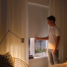 a man standing in front of a window looking out at the street outside his bedroom