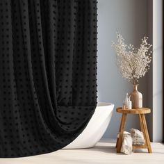 a white bath tub sitting next to a black curtain