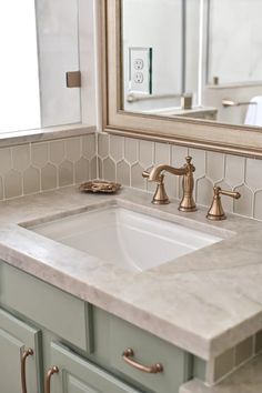 a bathroom sink sitting under a mirror next to a counter top with two faucets